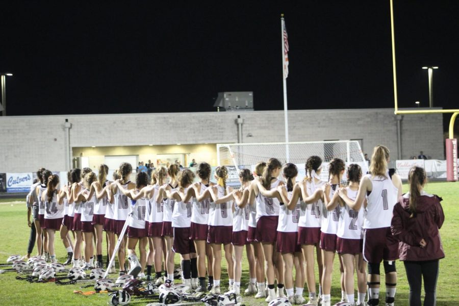 Lacrosse team stands together for the national anthem.