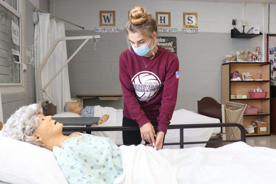 Senior CNA student, Holly Elfering, practicing her nursing skills on a mannequin. 