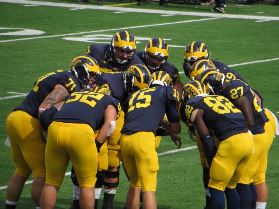 The Michigan Wolverines Quarterback telling teammates what the next play is in the huddle.