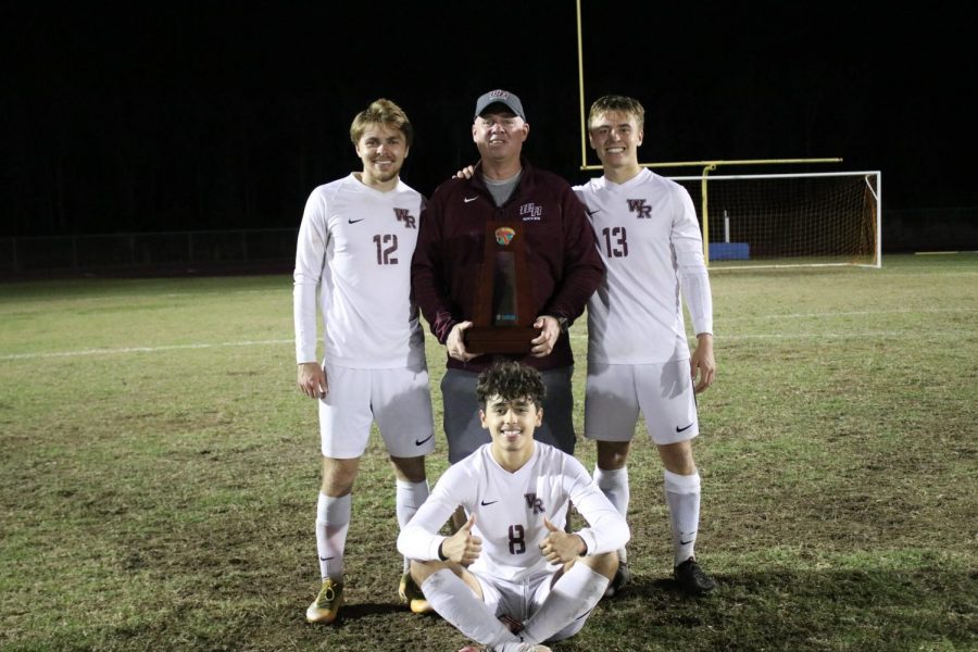 Patrick Amis (12), Coach Wilson, Justin Amis (13), Sammy Salas (8), tri-captains and head coach pose with the district trophy. 