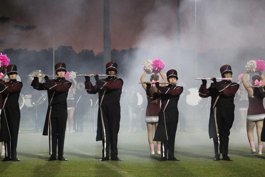 The band performing as the football team enter the stadium.