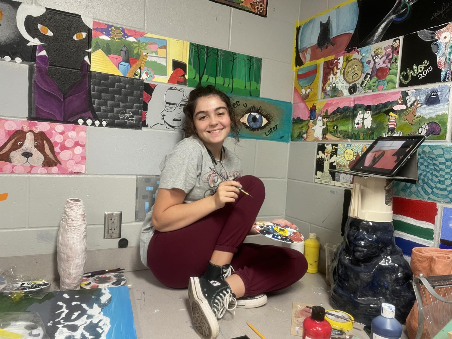 A photo of Olivia Robertson taken in her art class amidst painting her own wall tile.