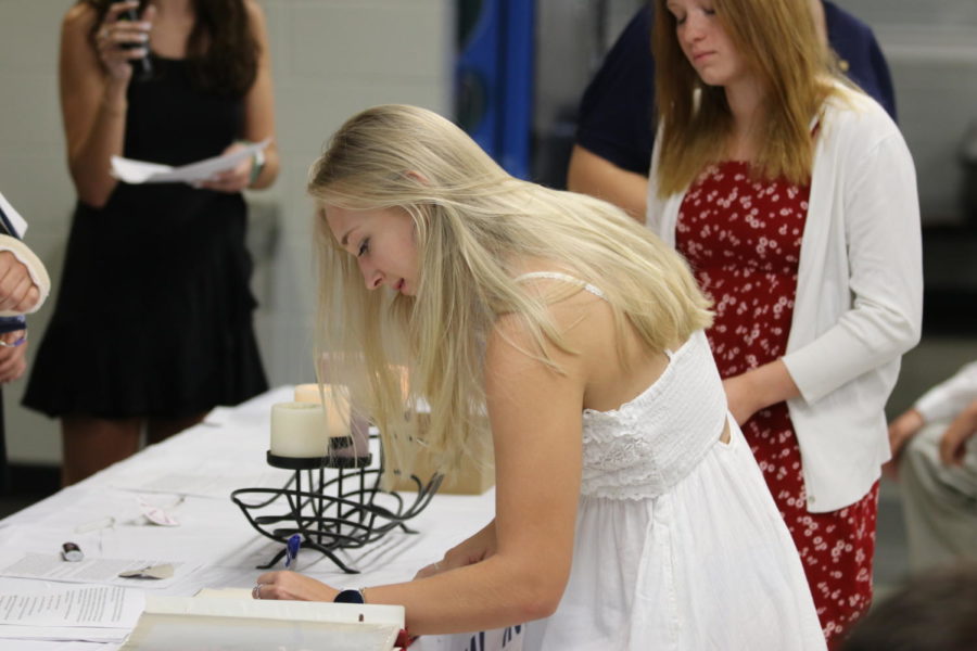 NHS member Alysa Bodanza signing her name in the National Honor Society book.