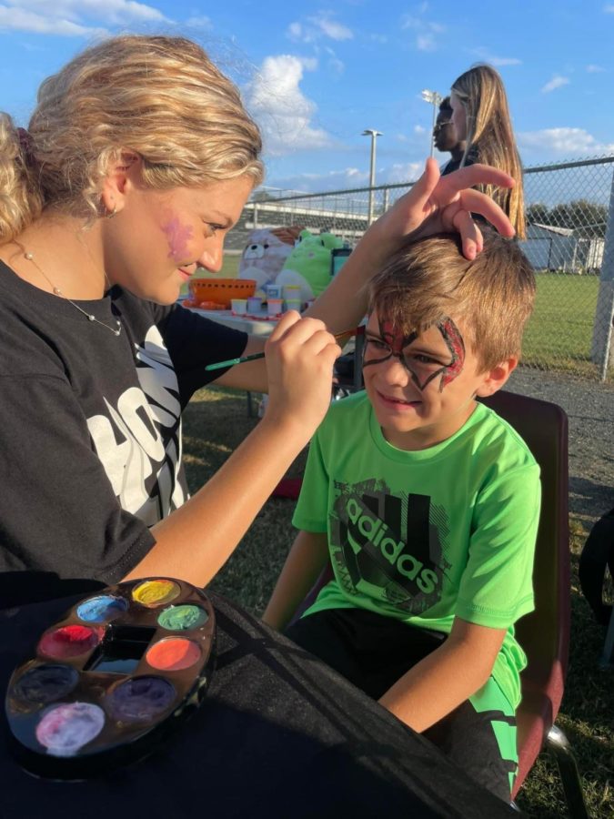 Bulls Nation member Brooke Bolli paints a childs face during the festival.