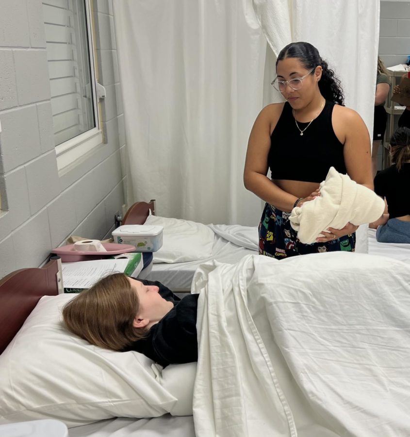 Two CNA students practice their nursing skills before their final exams.